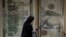 FILE - An Egyptian woman walks past an exchange office in Cairo, Egypt, March 6, 2024. 