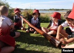 Pupils from the Gumbaynggirr Giingana Freedom School, a bilingual school teaching the Gumbaynggirr language, play with a didgeridoo during an outing in Urunga, Australia June 1, 2023. (REUTERS/Alasdair Pal)