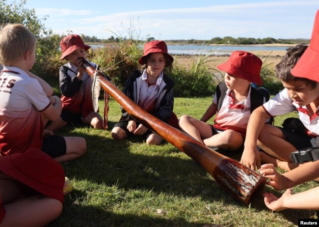 Pupils from the Gumbaynggirr Giingana Freedom School, a bilingual school teaching the Gumbaynggirr language, play with a didgeridoo during an outing in Urunga, Australia June 1, 2023. (REUTERS/Alasdair Pal)