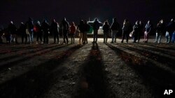 FILE - Migrants wait to be processed to seek asylum after crossing the border into the United States, Jan. 6, 2023, near Yuma, Ariz.