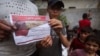 Palestinians hold leaflets dropped by Israeli planes calling on them to evacuate ahead of an Israeli military operation in Rafah, southern Gaza Strip, May 6, 2024.