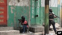 FILE - Police officers take cover during an anti-gang operation in Port-au-Prince, Haiti, April 25, 2023. Two journalists have been killed in Haiti in the past two weeks as gang violence has gripped Port-au-Prince and surrounding areas.