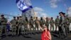 A demonstrator waves the Israeli flag seated on a highway while flanked by paramilitary border police during a protest against plans by Prime Minister Benjamin Netanyahu's government to overhaul the judicial system, in Tel Aviv, Israel, March 9, 2023.