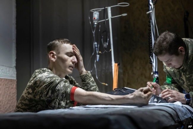 A medic gives first aid to a wounded Ukrainian soldier near Bakhmut, the site of the heaviest battles with the Russian troops, Donetsk region, Ukraine, Feb. 27, 2023.