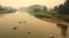 Sejumlah orang tampak berada di sungai Shuswap di saat asap dari kebakaran hutan menyelimuti lembah di wilayah Enderby, British Columbia, Kanada, pada 19 Agustus 2023. (Foto: Reuters/Chris Helgren)