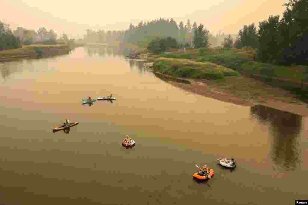 Луѓе во реката Шусвоп при магла предизвикана од чад од шумски пожар во Ендерби, Канада, 19 август 2023 година.