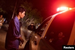 FILE - A migrant from China identifies himself to a U.S. Border Patrol agent after surrendering with a group that was smuggled across the Rio Grande into the United States from Mexico, in Fronton, Texas, April 4, 2023.