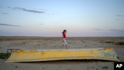 A girl plays on a worn-out boat along the dried-up Aral Sea, in the village of Tastubek, near Aralsk, Kazakhstan, July 2, 2023. 