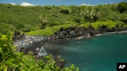 People spend time on the black sand beach at Waianapanapa State Park in Hana, Hawaii, on Sept. 24, 2014. (AP Photo/Marco Garcia, File)