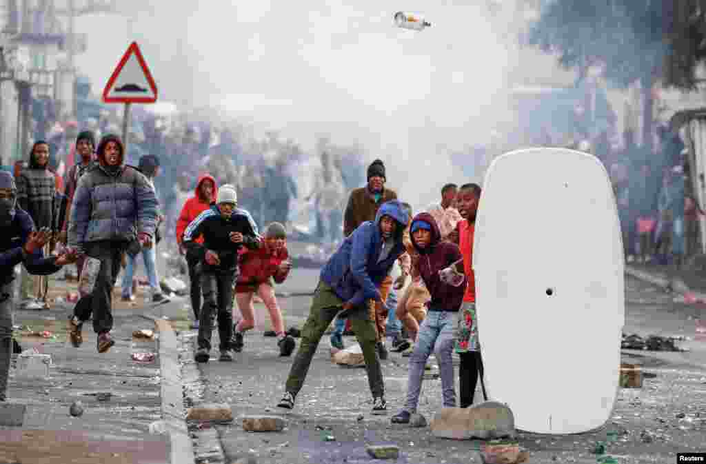 Residents of Masiphumelele throw bottles at police during an ongoing strike by taxi operators of traffic authorities, in Cape Town, South Africa.