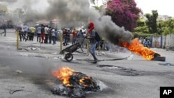 A man pushes a wheelbarrow past burning tires during a protest demanding the resignation of Prime Minister Ariel Henry in Port-au-Prince, Haiti, March 7, 2024.