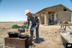 A man cooks fish caught from the remnants of the Aral Sea in a desert outside Muynak, Uzbekistan, June 24, 2023.