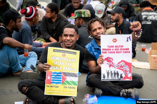 Dua orang pria Papua menunjukkan poster bertuiiskan "kemerdekaan adalah hak segala bangsa" dalam demonstrasi menuntut referendum kemerdekaan Provinsi Papua di Jakarta, 1 Desember2023. (Foto: Bay Ismoyo/AFP)
