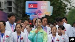 22일 중국 항저우 아시안게임 선수촌 환영식에서 자원봉사자가 북한 인공기를 들고 입장하고 있다.