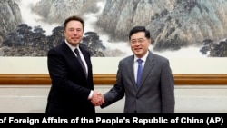China's Foreign Minister Qin Gang, right, poses with Tesla CEO Elon Musk in Beijing, May 30, 2023. (Ministry of Foreign Affairs of the People's Republic of China via AP)