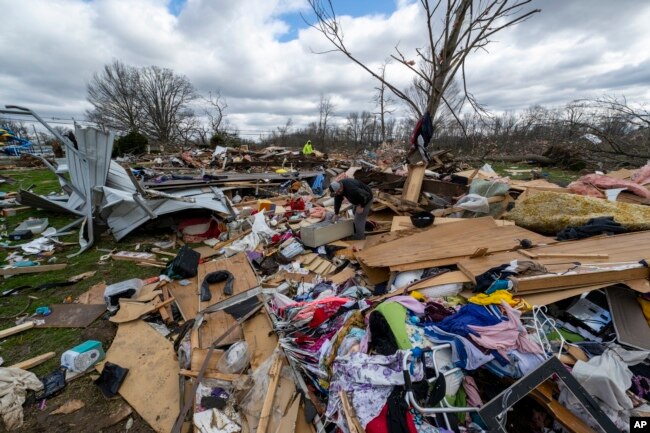 People walk through damage from a late-night tornado in Sullivan, Ind., April 1, 2023. (AP Photo/Doug McSchooler, File)