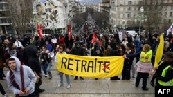 FILE: Protesters hold a yellow banner which reads "Pension", with a crossed 'E' at the end of the word 'retraite', which means in French "removal," during a demonstration, on March 18, 2023, two days after the government pushed a age change through parliament without a vote.