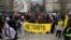 FILE: Protesters hold a yellow banner which reads "Pension", with a crossed 'E' at the end of the word 'retraite', which means in French "removal," during a demonstration, on March 18, 2023, two days after the government pushed a age change through parliament without a vote.