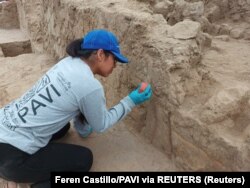 Seorang arkeolog sedang mengamati dinding polikrom berusia 4.500 tahun, bagian dari kuil milik periode Prakeramik Akhir, di Huaca Tomabal di Lembah Viru, Peru, 24 Agustus 2023. (Foto: Feren Castillo/PAVI via REUTERS)