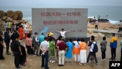 到中国福建省平潭岛旅游的游客参观台湾海峡边树立起的一块距离台湾68海里的石碑。（2024年1月13日）