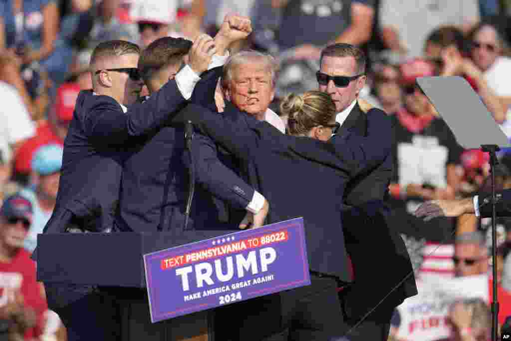 Former President Donald Trump is helped off the stage.