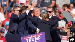 Republican presidential candidate former President Donald Trump is helped off the stage at a campaign event in Butler, Pennsylvania, July 13, 2024.