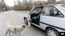 Jevgenij Markevič, 85-godišnji bivši učitelj, razgovara sa svojim psom dok se sprema da vozi u zoni isključenja u Černobilju, Ukrajina, 14. aprila 2021.