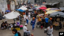 ARCHIVO - Vendedores y sus clientes en un mercado público en el barrio Quinta Crespo en Caracas, Venezuela, el domingo 11 de diciembre de 2022.