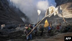 Villagers catch offerings thrown by members of the Tengger sub-ethnic group in the crater of the active Mount Bromo volcano as part of the Yadnya Kasada festival in Probolinggo, East Java province, Indonesia.