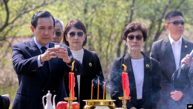 In this photo released by Xinhua News Agency, former Taiwan President Ma Ying-jeou, left, makes a libation as he pays respect to his grandfather's tomb in Xiangtan county, China, April 1, 2023.