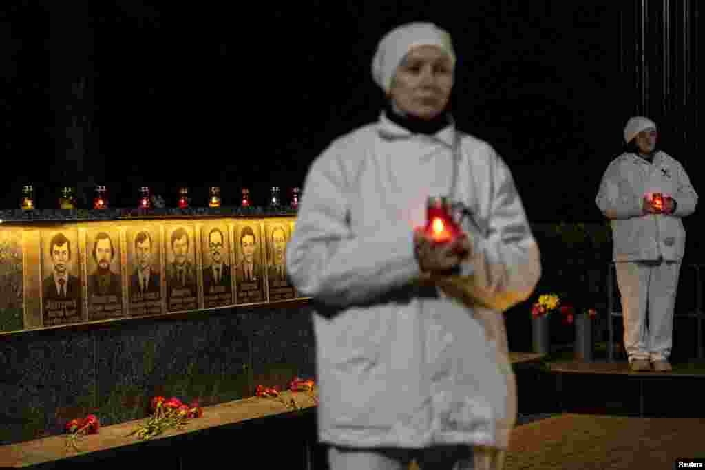 Workers at the Chernobyl nuclear plant hold candles at a memorial dedicated to firefighters and workers who died after the Chernobyl nuclear disaster in 1986, during a night commemorative service in Slavutych, Ukraine.