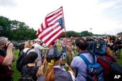 FILE - A woman holds an upside-down U.S. flag before a rally in Washington, Sept. 18, 2021. The rally was planned by allies of former President Donald Trump and aimed at supporting the "political prisoners" of the January 6 U.S. Capitol insurrection.