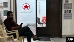 一位男士坐在新德里的加拿大航空公司地区办事处外查看自己的手机。(2023年9月20日)