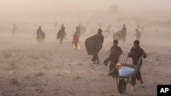 Afghans receive aid while a sandstorm rages at the Chahak village, after an earthquake in Zenda Jan district in Herat province, western of Afghanistan, Oct. 12, 2023. The Afghan Taliban has reportedly blocked earthquake-related aid from Pakistan over a post on social media.