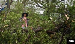 Una mujer se encuentra en medio de árboles caídos en Kyauktaw, en el estado de Rakhine, en Myanmar, el 14 de mayo de 2023, después de que el ciclón Mocha tocara tierra.