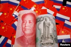 Uang kertas yuan China dan rubel Rusia terlihat di tengah bendera China dan Rusia. (REUTERS/Florence Lo)