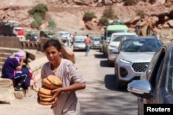 A girl carries bread received from a volunteer as people in vehicles wait for the road to be cleared from debris in the aftermath of a deadly earthquake near the village of Tallat n'Yakoub, Morocco, Sept. 12, 2023