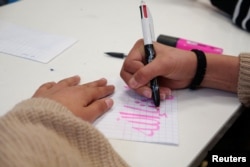 A middle school student scribbles on a piece of paper during an Islamic ethics class at the Averroes school, France's biggest Muslim educational institution that has lost its state funding, Lille, France, March 19, 2024.