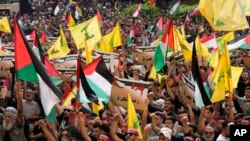 Pendukung Hizbullah mengibarkan bendera Lebanon, Palestina dan kelompoknya, sambil memegang plakat pro-Gaza dalam protes untuk menunjukkan solidaritas mereka terhadap Palestina, di pinggiran selatan Beirut, Lebanon, Jumat, 13 Oktober 2023. (AP/Hussein Malla)