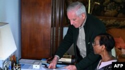 Alain Gauthier (back) grabs documents next to his wife Dafroza, Rwandan genocide-hunters and founders of Collective of Civil Parties for Rwanda, five days before the commemorations for its 30th anniversary in their home in Reims on March 26, 2024.