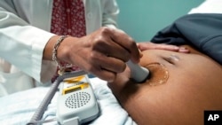 FILE - A doctor uses a hand-held probe on a pregnant woman to measure the heartbeat of her fetus, in Jackson, Mississippi, Dec. 17, 2021.