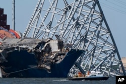 A boat moves past the bow of the container ship Dali prior to the detonation of explosive charges to bring down sections of the collapsed Francis Scott Key Bridge resting on the Dali on May 13, 2024, in Baltimore.