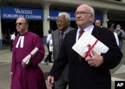 FILE - Actor Ed Asner, right, along with the Rev. Don Brown, left, and the Rev. James Lawson, center, walk to the Capitol, in Sacramento, Calif. carrying petitions calling for a 