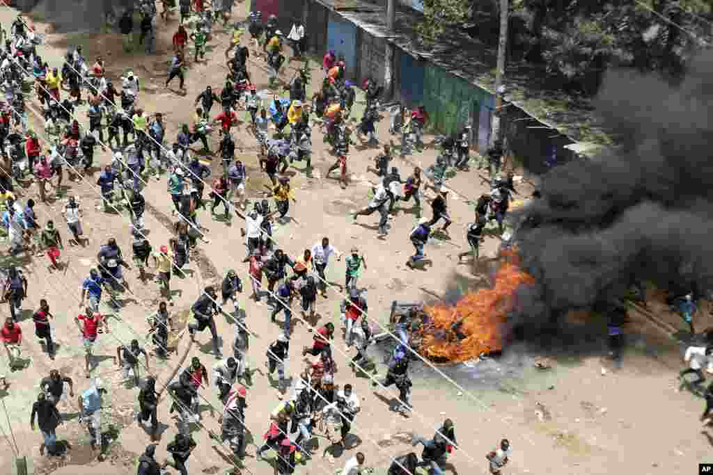 Protesters run towards riot police officers during a mass rally called by the opposition leader Raila Odinga over the high cost of living in Kibera Slums, Nairobi, Monday, March 27, 2023.