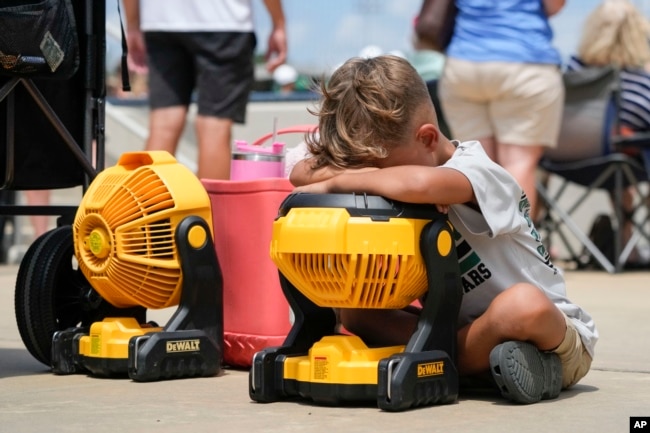 FILE - Braxton Hicks, 7, of Livingston, Texas, holds his face to a portable fan to cool off during a baseball tournament in Ruston, La., Aug. 9, 2023. (AP Photo/Gerald Herbert)