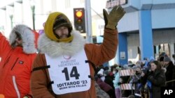Defending champion Brent Sass, wearing bib No. 14, waves to the crowd during the Iditarod Trail Sled Dog Race's ceremonial start in downtown Anchorage, Alaska, on March 4, 2023.