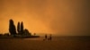 ARCHIVO - El humo del incendio de McDougall Creek llena el aire mientras dos personas miran el paisaje en el lago Okanagan desde la playa Tugboat, en Kelowna, Columbia Británica, el 18 de agosto de 2023.