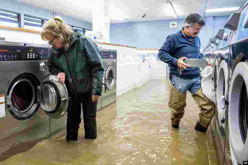 Pamela and Patrick Cerruti empty coins from the Pajaro Coin Laundry as floodwaters surround machines in the community of Pajaro in Monterey County, California, March 14, 2023.