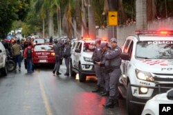 Polisi berjaga di sepanjang jalan menuju kawasan perumahan berpagar tempat pesawat jatuh di Vinhedo, negara bagian Sao Paulo, Brazil, Jumat, 9 Agustus 2024. (Andre Penner/AP)