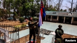 ทหารของกองกำลังปลดปล่อยชาติกะเหรี่ยง ขณะกำลังนำธงกะเหรี่ยงขึ้นสู่ยอดเสาที่หมู่บ้านตีงาหยี่หน่อง Thing Nga Nyi Naung Village เมืองเมียวดี แทนที่ธงเมียนมาที่เพิ่งเผาทำลายไป วันที่ 15 เมษายน 2024 (ที่มา: รอยเตอร์)
